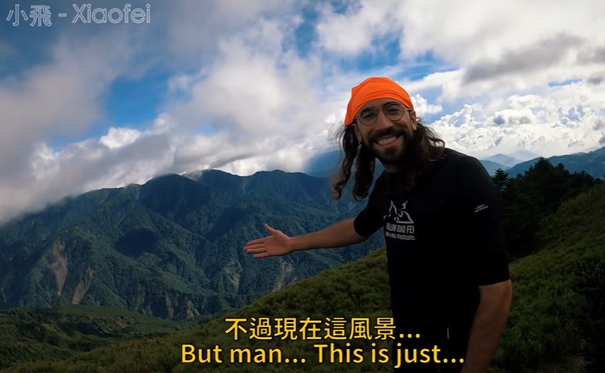 Ca sĩ Dave khi leo lên đến đỉnh và được nhìn ngắm vẻ đẹp của phong cảnh núi non hùng vĩ hiển hiện ngay trước mắt, đã rất cảm động đến gần rơi nước mắt. (Nguồn ảnh: kênh YouTube “Xiaofei小飛”)