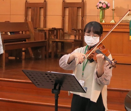 เจิ้งฉู่หง (鄭楚虹) ลูกหลานของผู้ตั้งถิ่นฐานใหม่ที่กำลังศึกษาอยู่ที่มหาวิทยาลัยจงซาน สาขาดนตรี ร่วมแสดงดนตรีที่มีชื่อเสียงอย่างเพลง “กั่นเอินเตอะซิน” (感恩的心)  ภาพจาก／สถานีบริการเมืองเจียอี้ กองพลกิจการพื้นที่ภาคใต้ สำนักงานตรวจคนเข้าเมือง