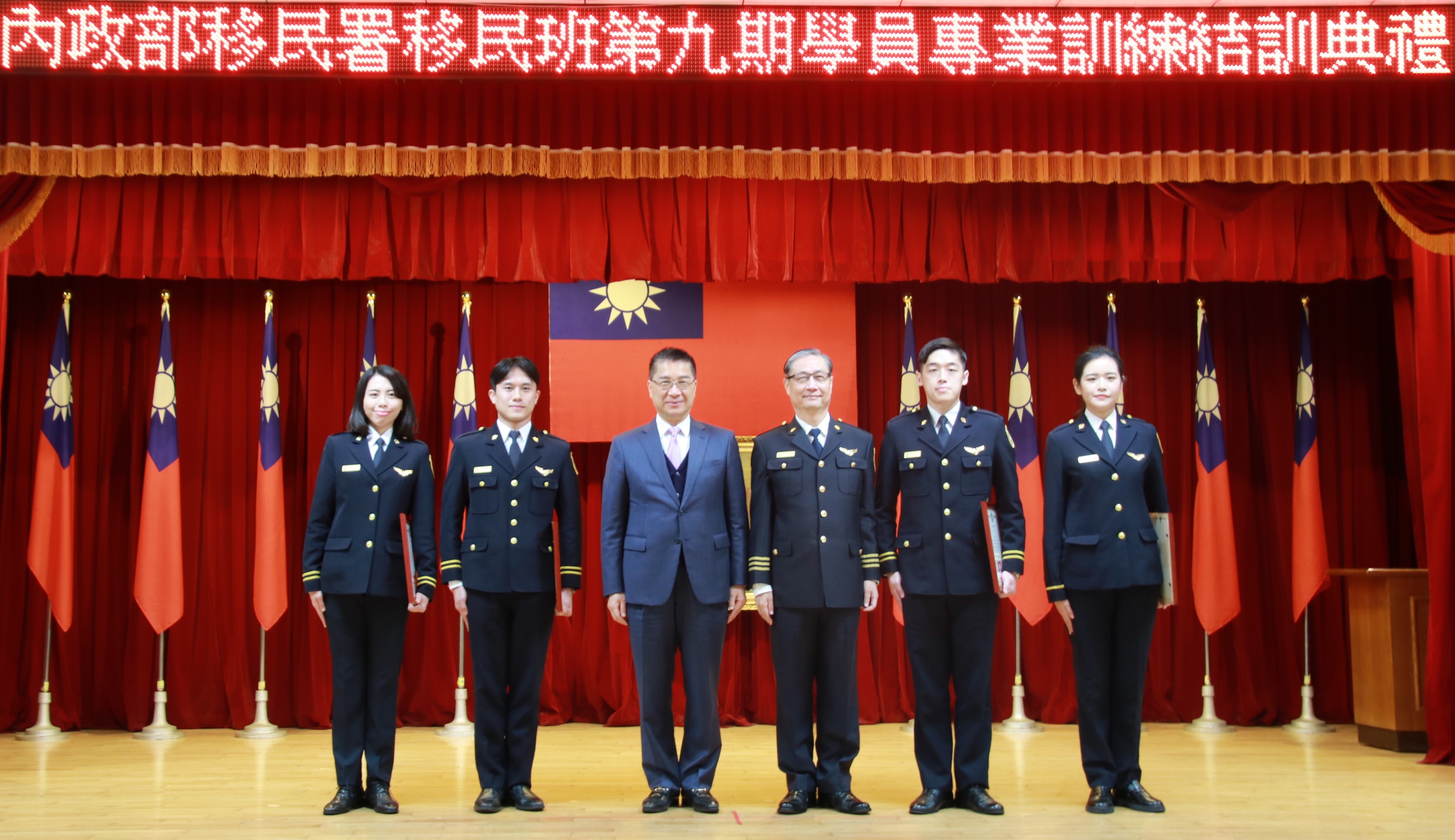 Menteri Dalam Negeri Xu Guoyong (徐國勇) ketiga dari kiri dan Direktur Departemen Imigrasi Zhong Jingkun (鐘景琨) keempat dari kiri berfoto bersama dengan pejabat imigrasi terkemuka. (Sumber: Departemen Imigrasi)