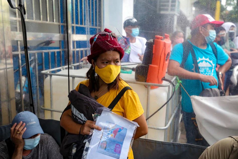 People hoping to get vaccinated take shelter at a “decontamination booth” after a sudden downpour at the San Andres Sports Complex in Manila on July 20, 2021. George Calvelo, ABS-CBN News