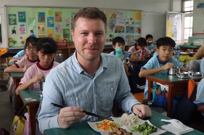 Wes Davies(衛斯理) mengunjungi sekolah SD Hesheng(鶴聲國小), makan siang bersama murid-murid.  Sumber: Diambil dari Wes Davies