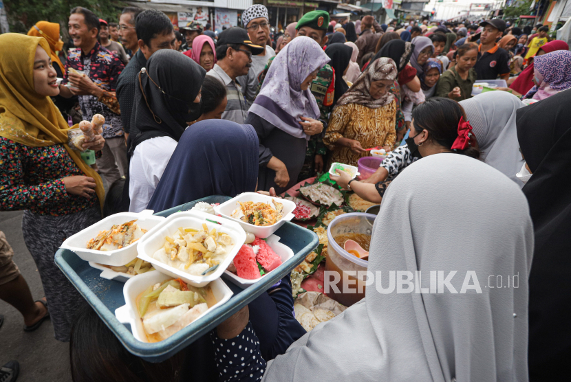 Warga antre untuk mendapatkan hidangan ketupat gratis di Kampung Sukolilo, Surabaya, Jawa Timur, Jumat (28/4/2023). Tradisi Lebaran Ketupat yang diadakan pada hari ketujuh setelah Hari Raya Idul Fitri tersebut dimeriahkan dengan membagikan berbagai hidangan ketupat secara gratis kepada warga sekitar sebagai ungkapan rasa syukur warga atas ibadah puasa Ramadhan yang berhasil dilalui.