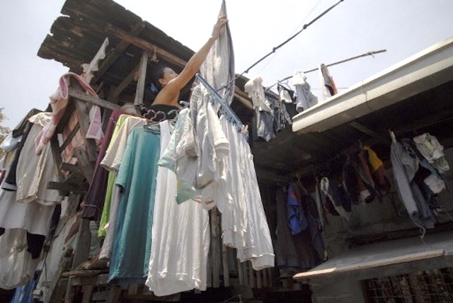 A woman hangs laundry from a window outside her shanty in Manila. A new city ordinance bans hanging clothes outside windows and other areas that cause visual clutter. Attribute: AFP