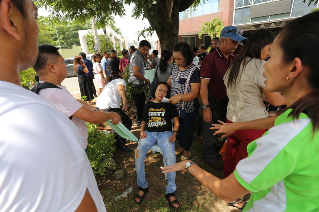 A woman in Davao City, the Philippines, was looked after by friends after fainting in the aftermath of an earthquake. Attribute: New York Times