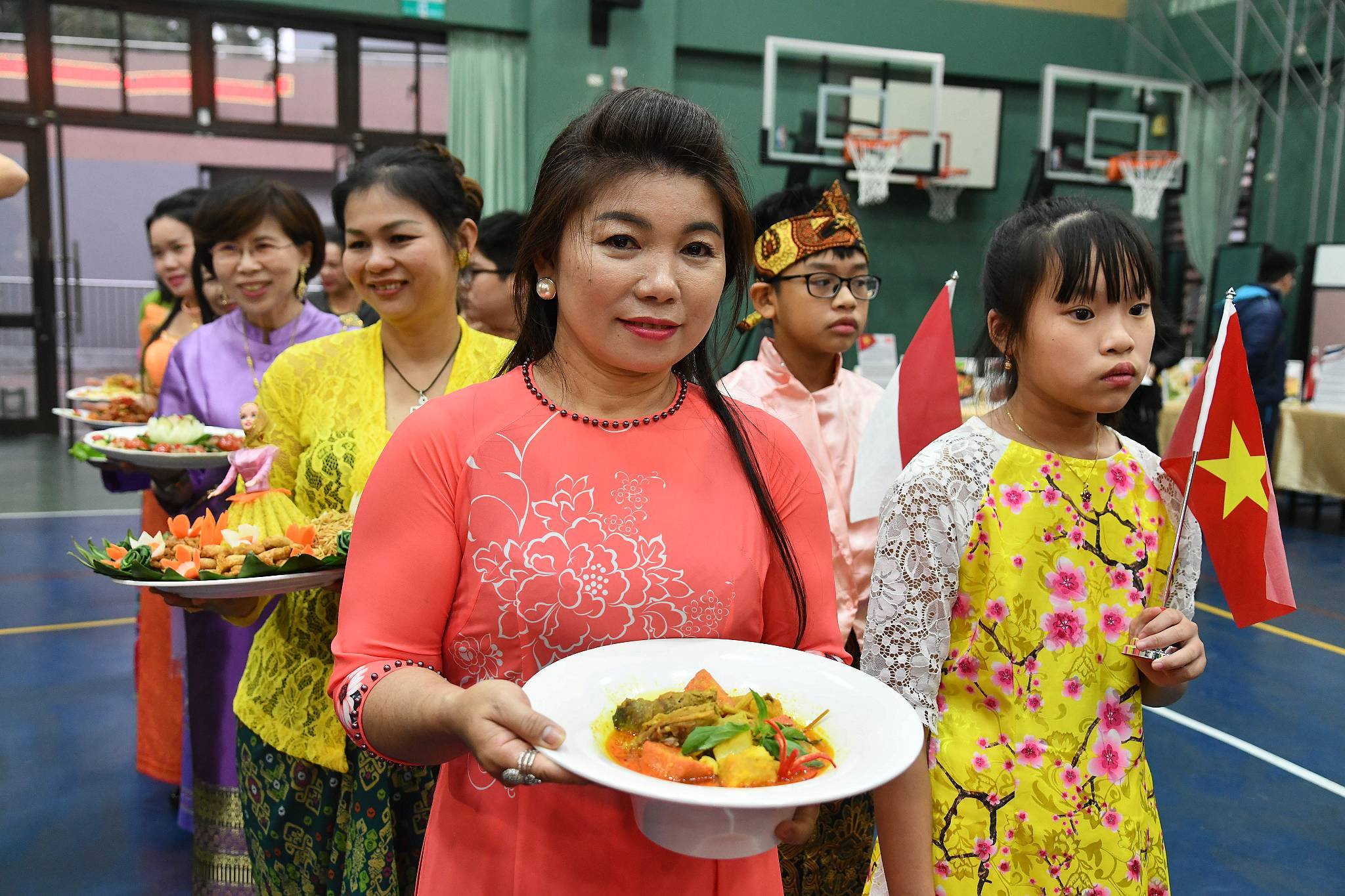 ผู้ตั้งถิ่นฐานใหม่จาก 7 ประเทศ สวมชุดประจำชาติของตนเองและนำเสนออาหารแบบดั้งเดิมของประเทศตนเองแก่เด็กนักเรียน (ภาพจาก รัฐบาลนครนิวไทเป)