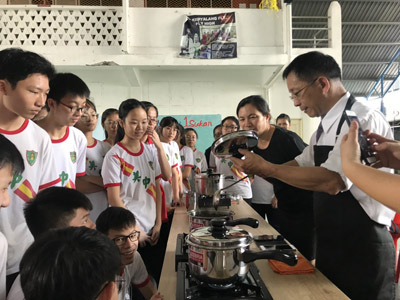 大葉大學烘焙學程張立功老師(右一)向美里中華中學的學生介紹珍珠奶茶裡的粉圓(翻攝自大葉大學網站)