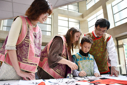 นักเรียนต่างชาติสวมเสื้อกั๊กจีนโบราณ และร่วมกันสัมผัสการเขียนศิลปะตัวอักษรจีน (ภาพจาก มหาวิทยาลัยการแพทย์เกาสง)