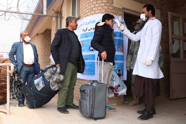 Nhân viên y tế Afghanistan kiểm tra nhiệt độ hành khách từ Iran tại khu vực biên giới ở Herat