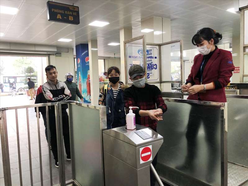 Hành khách được rửa tay sát khuẩn và phát khẩu trang miễn phí khi qua cửa soát vé tại bến Giáp Bát. Ảnh: T.Đảng