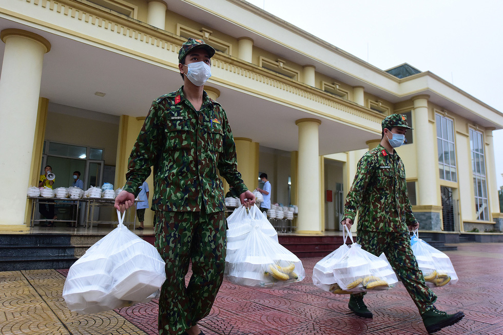 Hai chiến sĩ tại Trường Quân sự Bộ tư lệnh Thủ đô chuyển các túi cơm hộp vào khu vực tập kết trước khi được chia cho những người dân bị cách ly