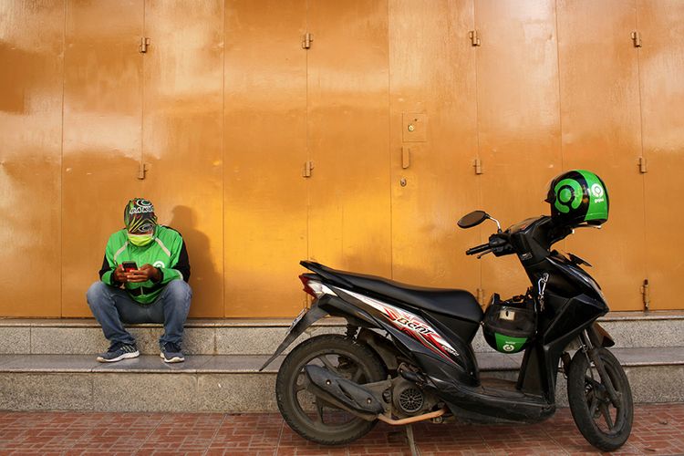 Pengemudi ojek daring menunggu pesanan di Makassar, Sulawesi Selatan, Sabtu (4/4/2020).