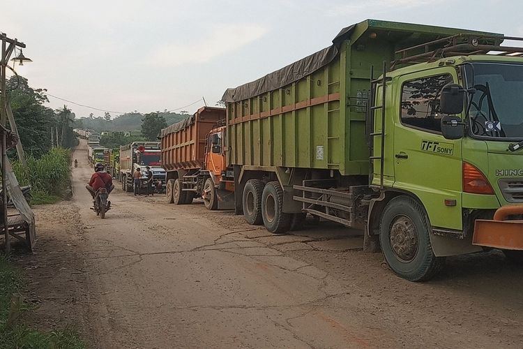 Seorang pengendara melintas di samping truk tronton angkutan tambang yang berhenti untuk melanjutkan perjalanannya dari arah Jalan Sudamanik menuju perbatasan jalan raya Parung Panjang.(KOMPAS)