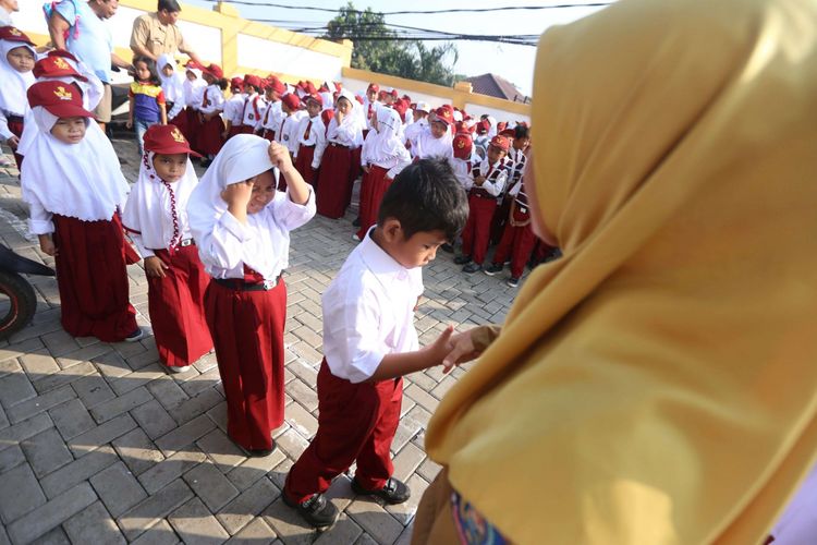 Guru bersalaman dengan murid baru (KOMPAS)