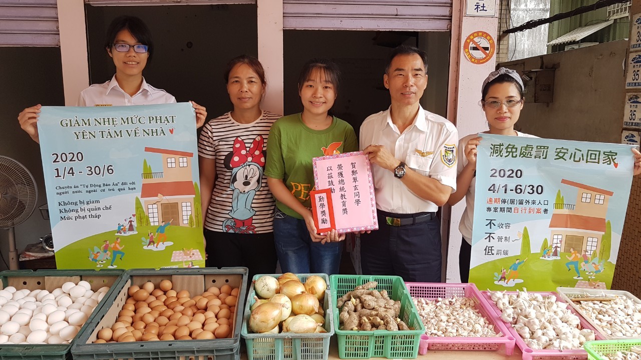 Ông Giản Thông Châu - Giám đốc Trạm phục vụ Sở Di dân huyện Nghi Lan (bên phải thứ 2) đến sạp bán rau củ của Trịnh Thúy Huyền (giữa) và mẹ của em (bên trái thứ 2) trao quà thưởng chúc mừng Huyền đạt「Giải thưởng giáo dục Tổng thống 2020」